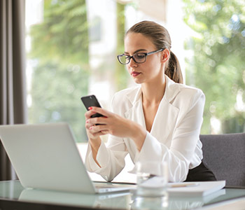 Business woman using phone and laptop